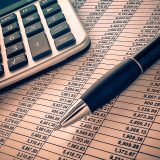 Calculatrice, stylo et tableau de chiffres pour préparer le budget du tour du monde