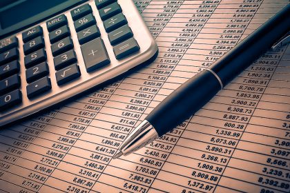 Calculatrice, stylo et tableau de chiffres pour préparer le budget du tour du monde