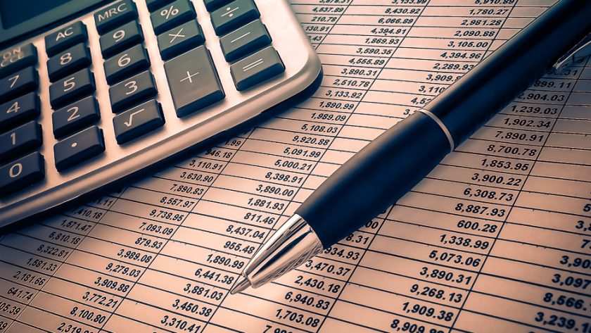 Calculatrice, stylo et tableau de chiffres pour préparer le budget du tour du monde
