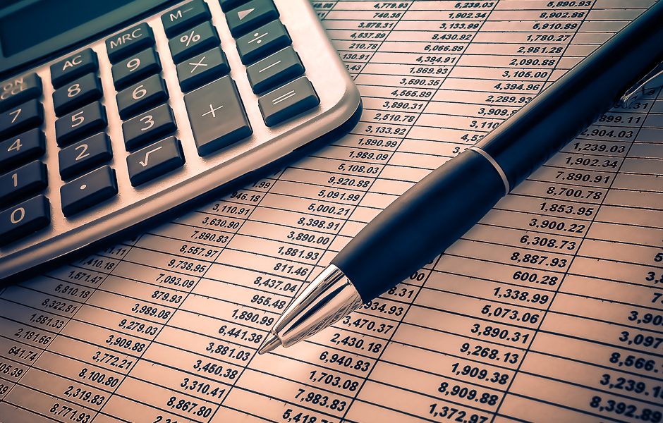 Calculatrice, stylo et tableau de chiffres pour préparer le budget du tour du monde
