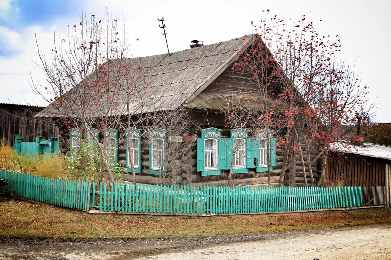 Maison en bois aux volets turquoise dans un village sibérien
