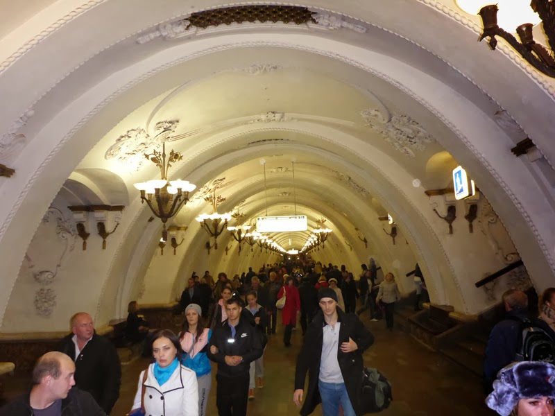 Foule sous la voûte blanche et les lustres d’une station moscovite