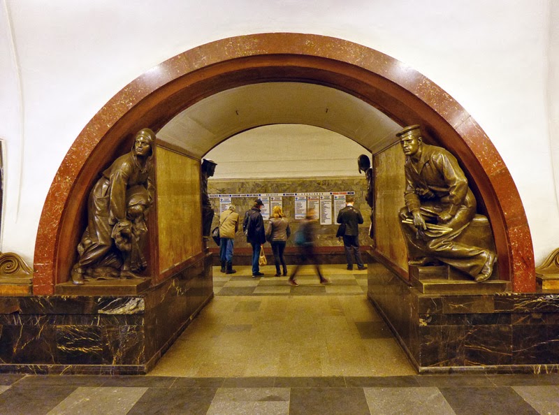 Arche de marbre encadrée de statues de bronze dans une station du métro de Moscou