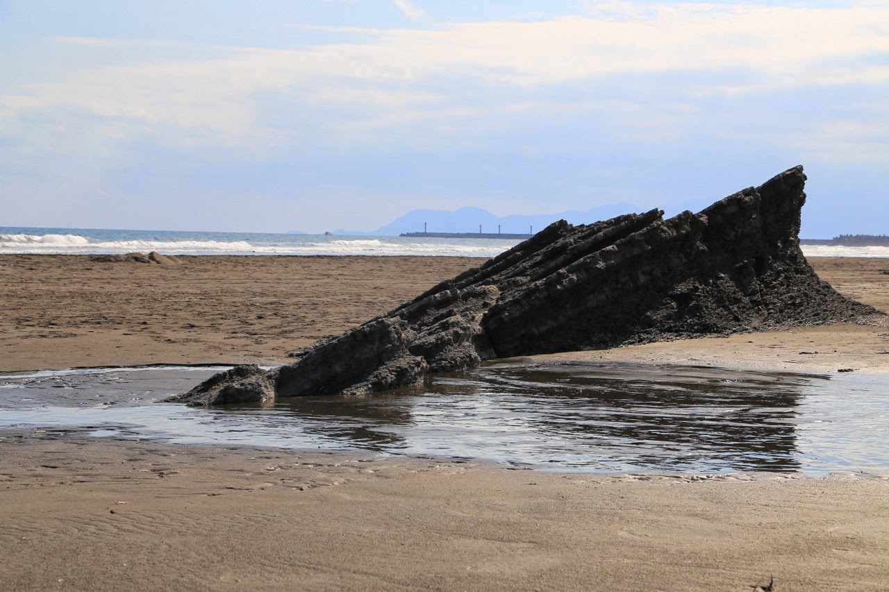 Rocher échoué sur la plage de sable noir