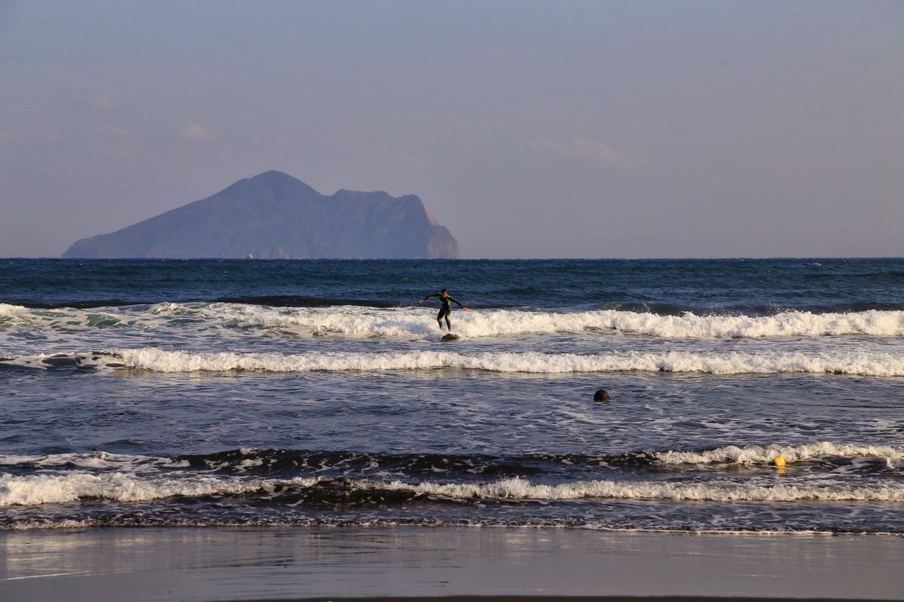 Surfeurs et île de la Tortue au large de Wai Ao