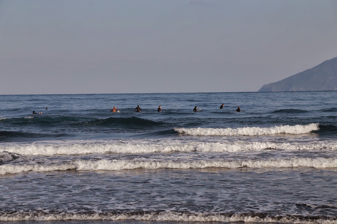 Vagues et surfeurs sur la plage de sable noir