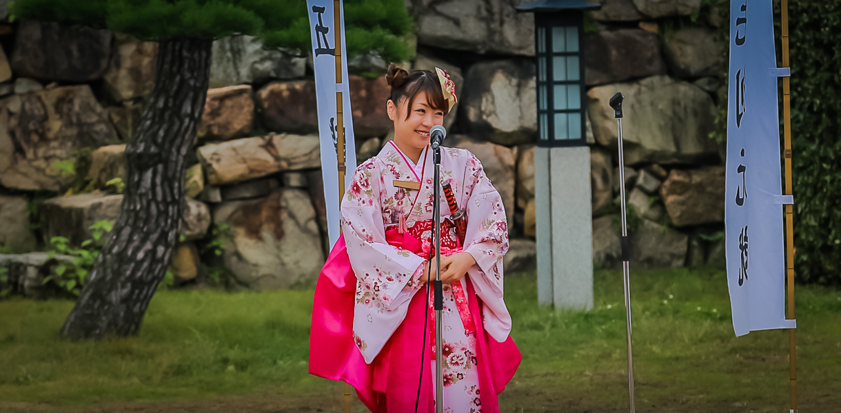 Jeune fille en kimono rose devant un mur de pierres
