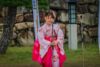 Jeune fille en kimono rose devant un mur de pierres