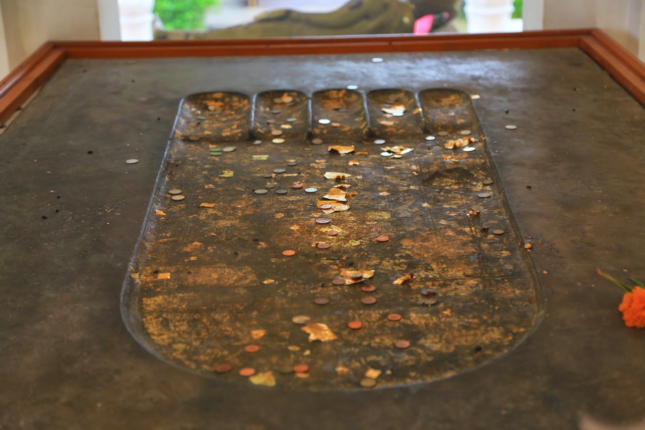 Empreinte du pied de Bouddha recouverte de pièces