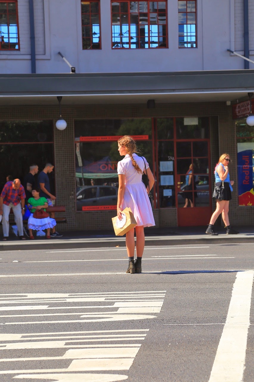 Passante en robe blanche devant une vitrine de Newtown
