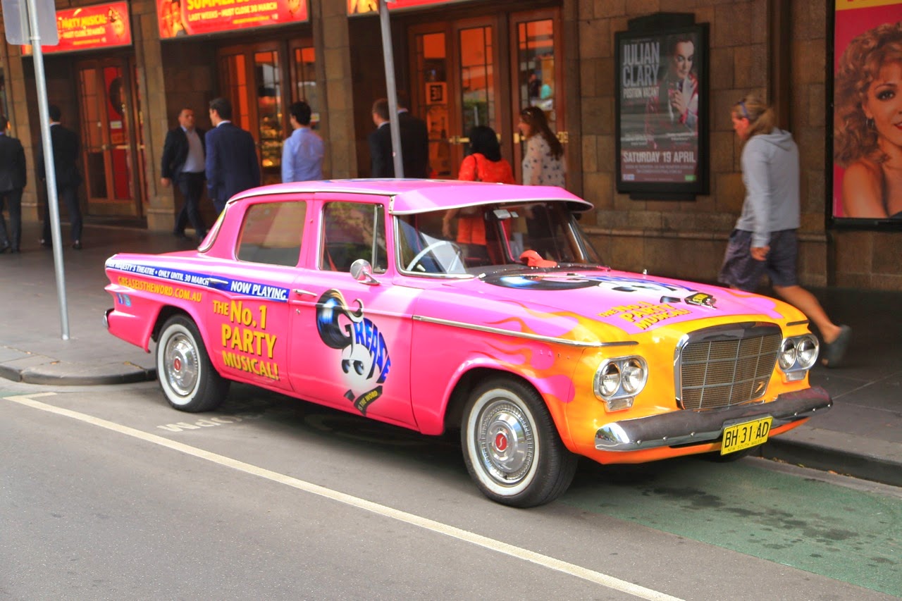Voiture ancienne rose dans une rue
