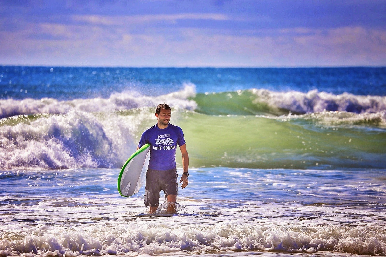 Surfeur debout dans l’écume avec sa planche