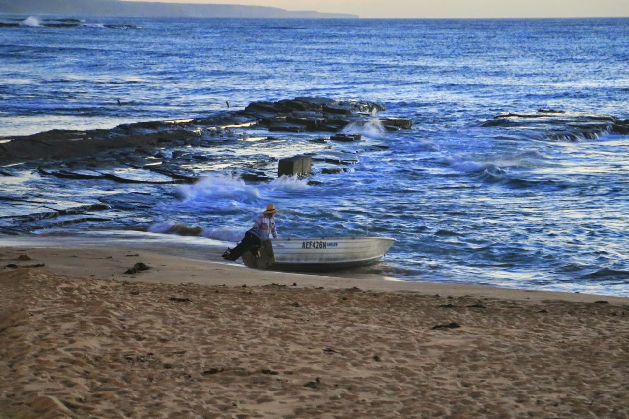 Pêcheur et sa barque sur une plage rocheuse