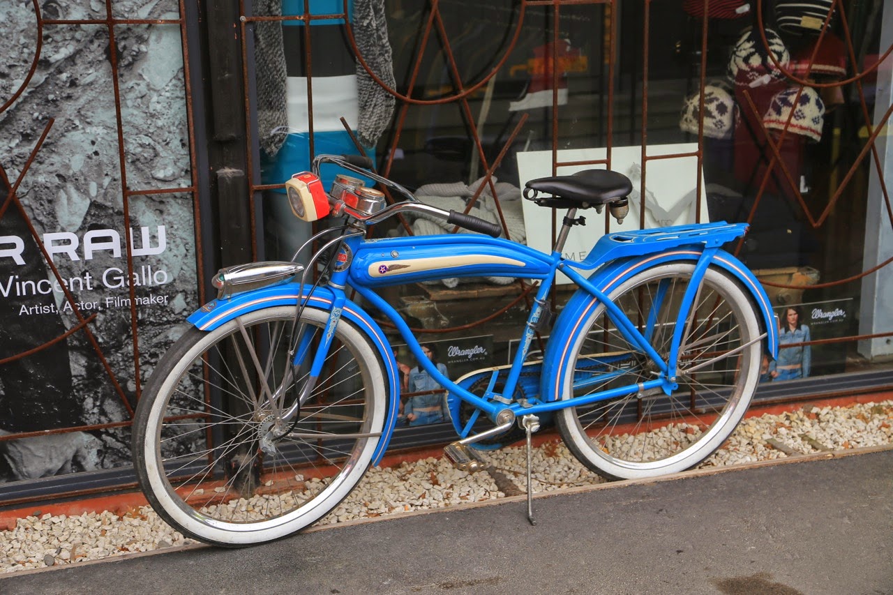 Vélo bleu rétro devant une vitrine