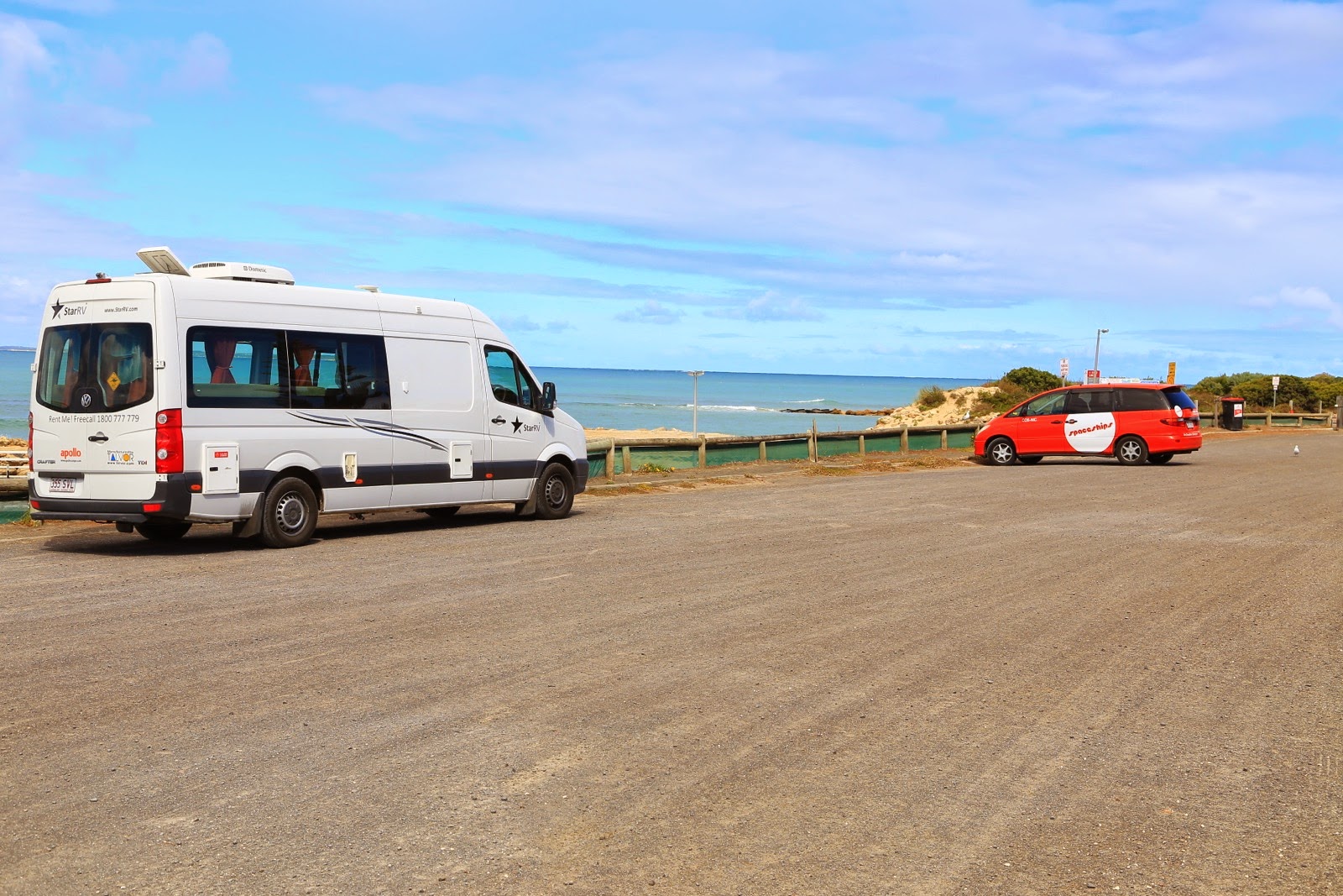 Grand van VW et petit van Toyota sur un parking en bord de mer