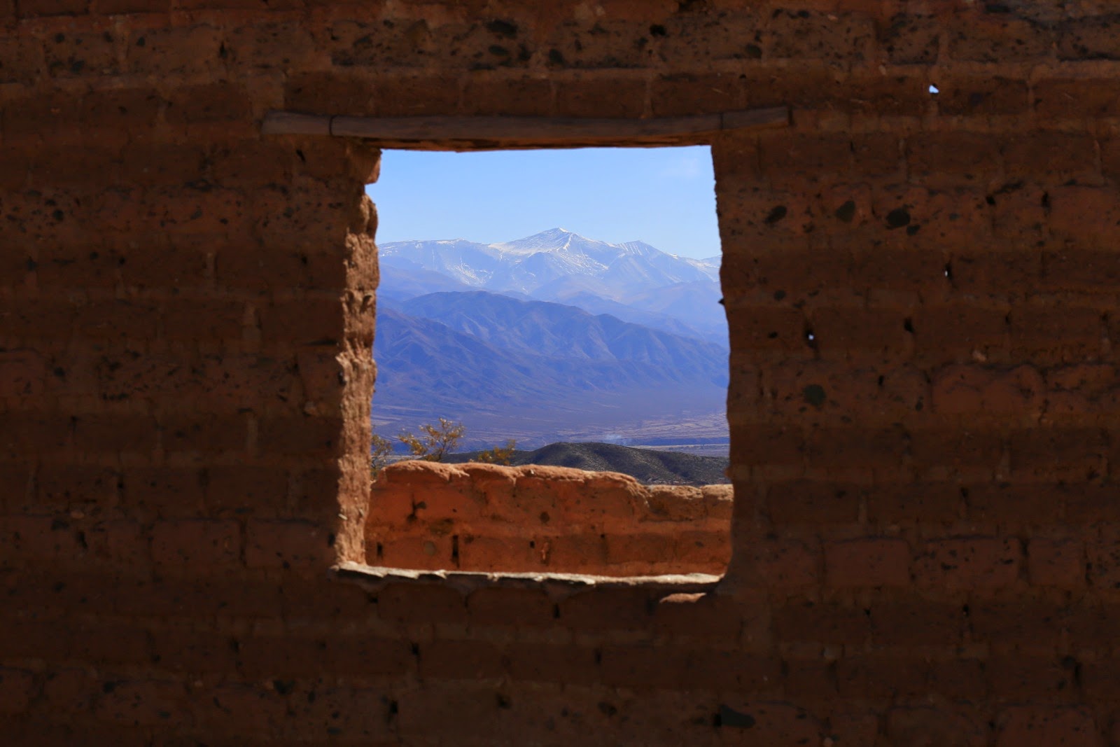 Montagnes enneigées à travers une fenêtre en adobe