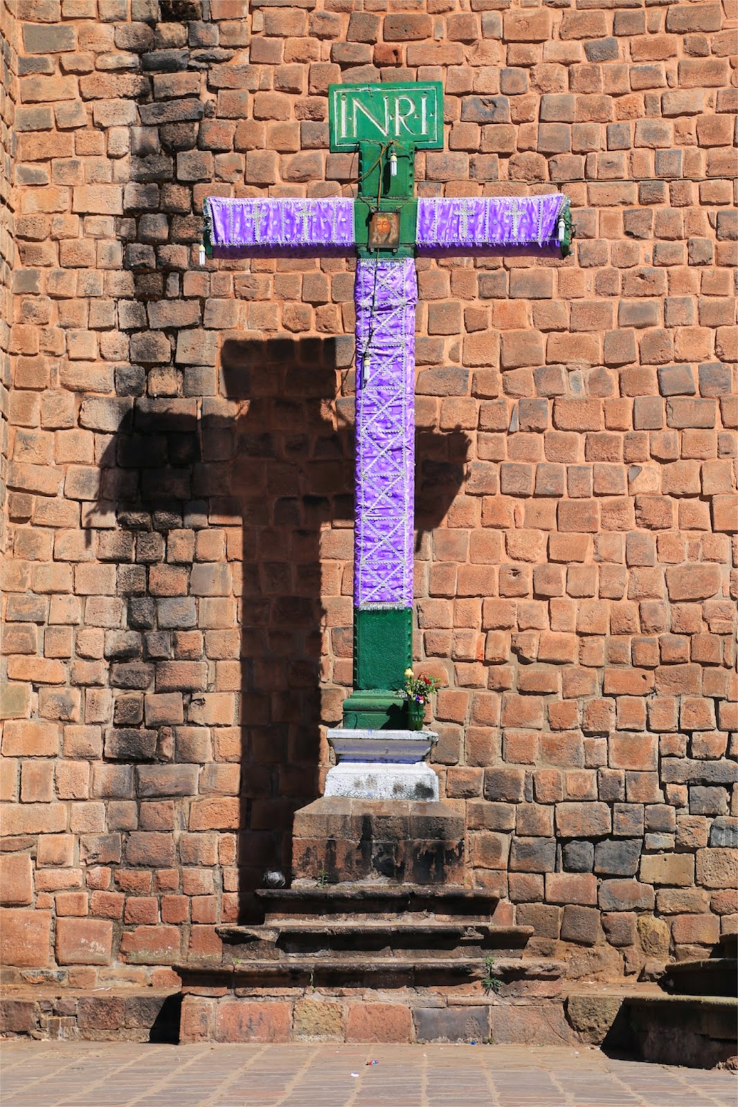 Croix en pierre devant un mur inca