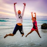 Couple sautant de joie sur une plage au coucher du soleil, souvenir de notre tour du monde
