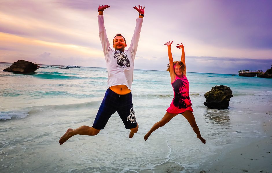 Couple sautant de joie sur une plage au coucher du soleil, souvenir de notre tour du monde