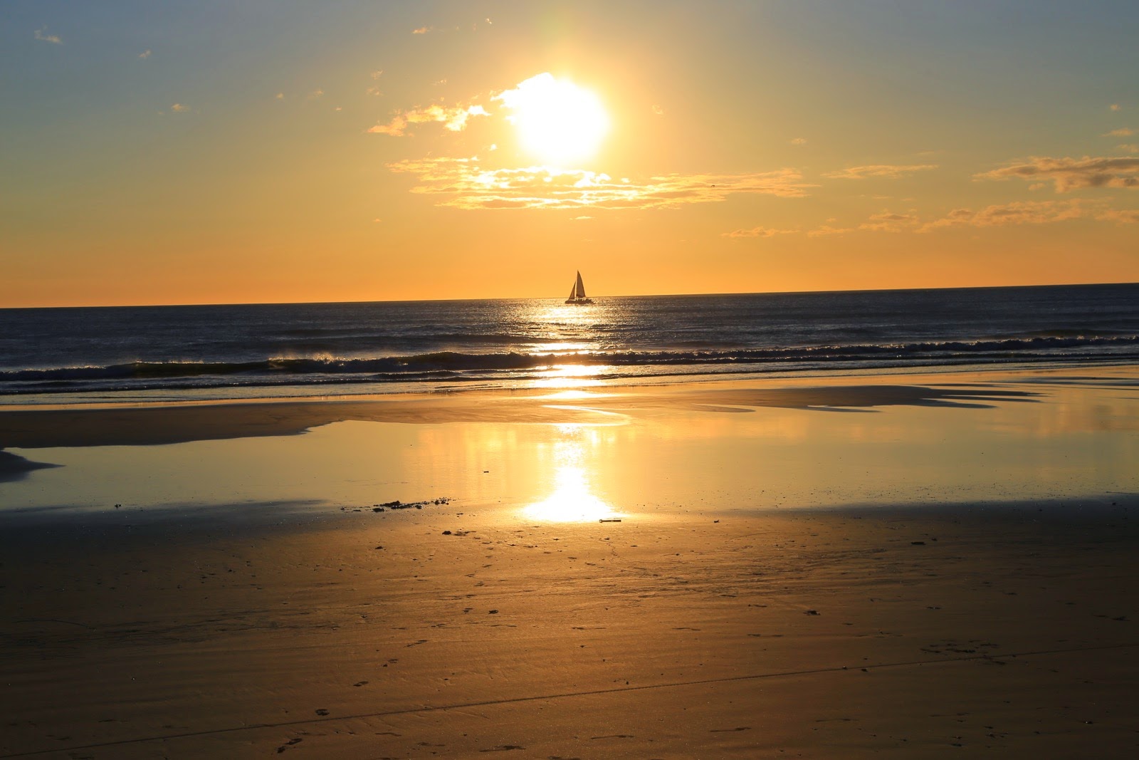 Un voilier au large au coucher du soleil