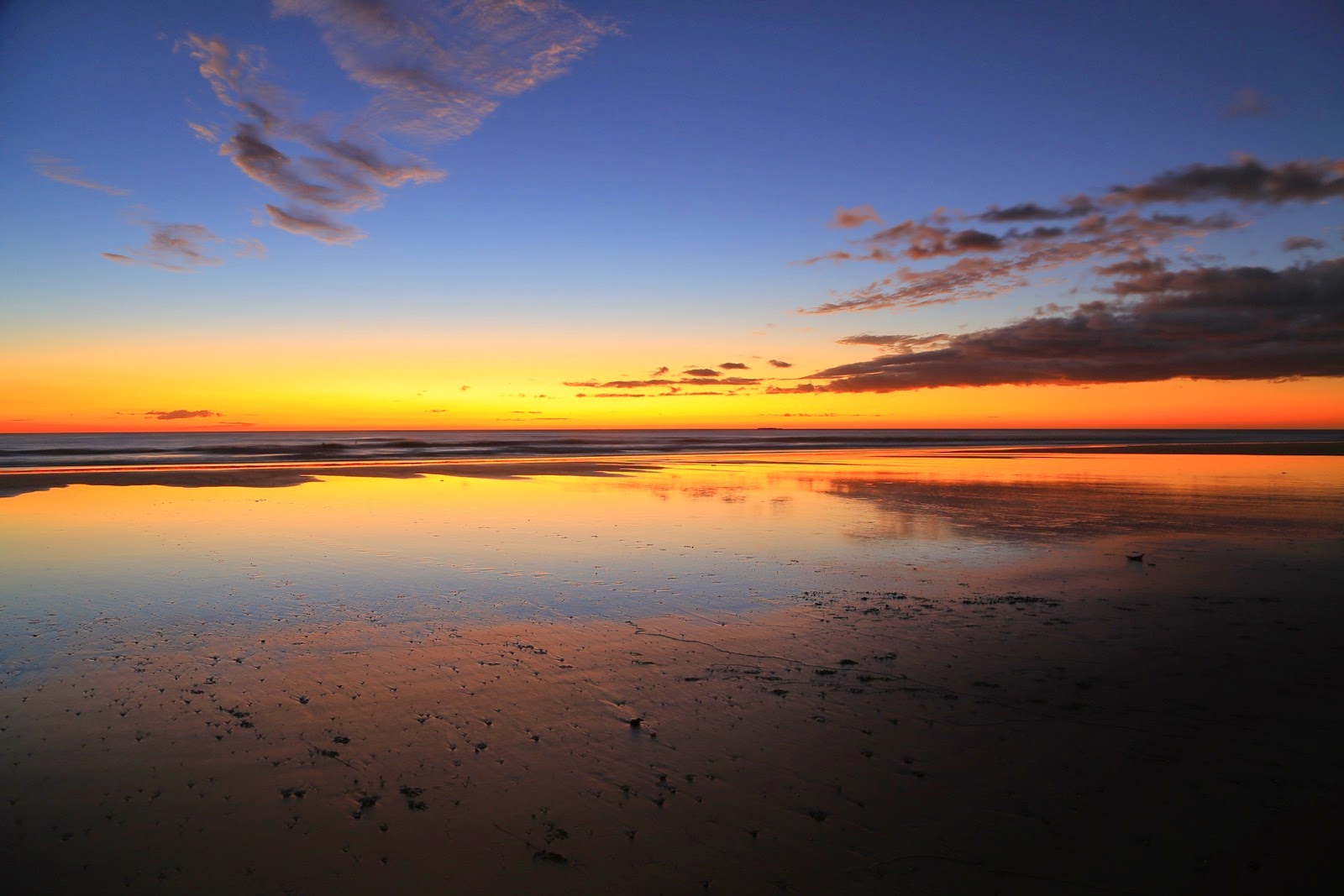 Le ciel du soir se reflète sur le sable mouillé