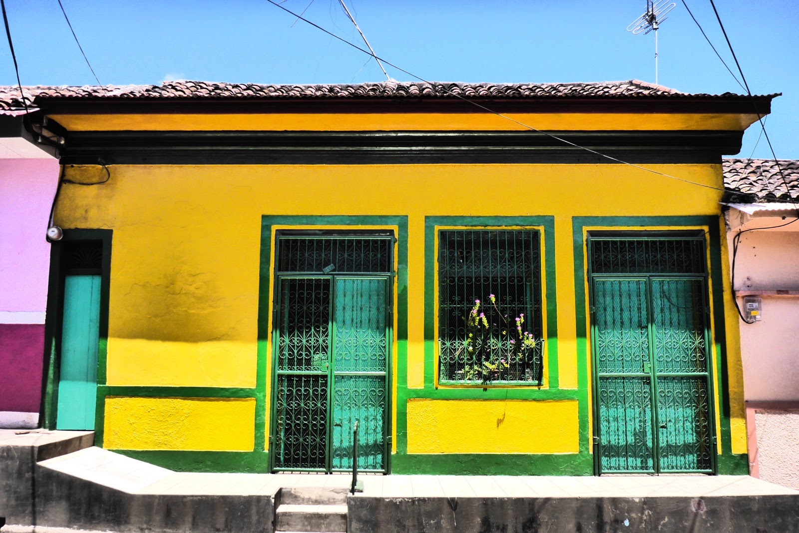Maison jaune aux grilles vertes