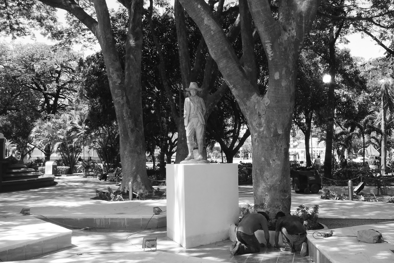Statue dans un parc ombragé, en noir et blanc