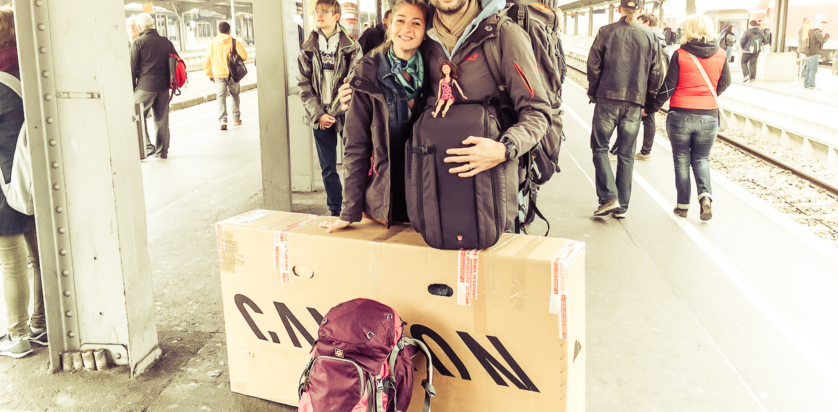 Voyageurs sur un quai de gare avec un vélo emballé dans un carton pour le voyage