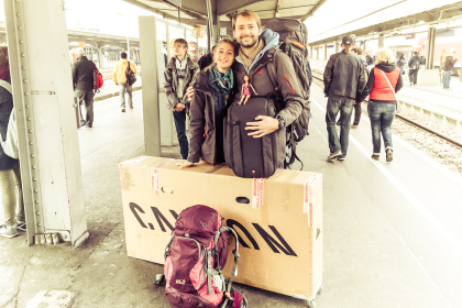Voyageurs sur un quai de gare avec un vélo emballé dans un carton pour le voyage