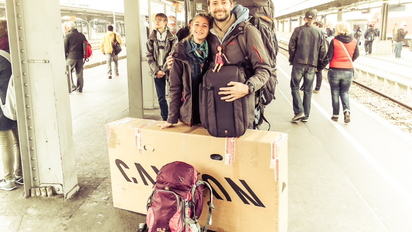 Voyageurs sur un quai de gare avec un vélo emballé dans un carton pour le voyage