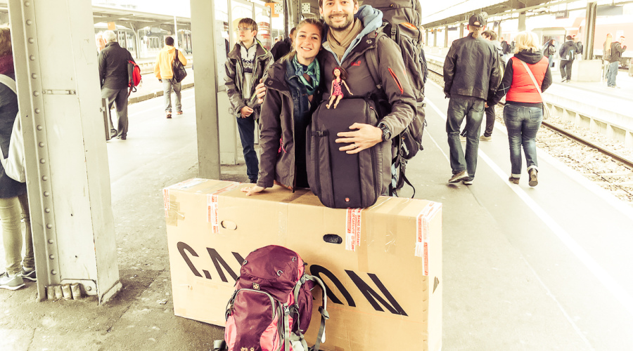 Voyageurs sur un quai de gare avec un vélo emballé dans un carton pour le voyage
